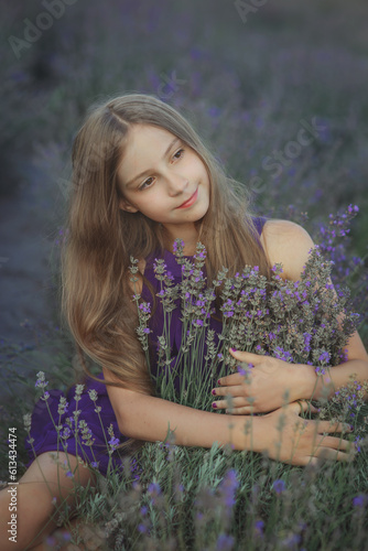 Young pretty dreaming girl in violet dress sitting in lavender field hugging flowers in Provence at sunset, vertical outdoor lifestyle portrait, idea of beauty, tenderness, relax and summer vibe