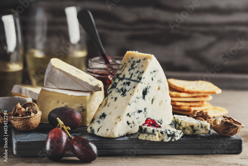 Photos Different arts of cheese with grape on wooden