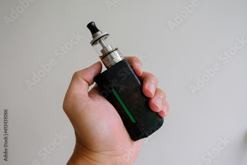 hand holding vaporizer, vape or electric cigarette on white background