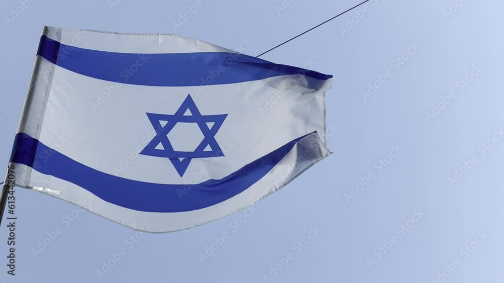 Israeli flag white and blue with star Magen David fluttering in wind on blue sky. outdoor. Israeli flag white and blue with star Magen David fluttering in wind on blue sky. outdoor.