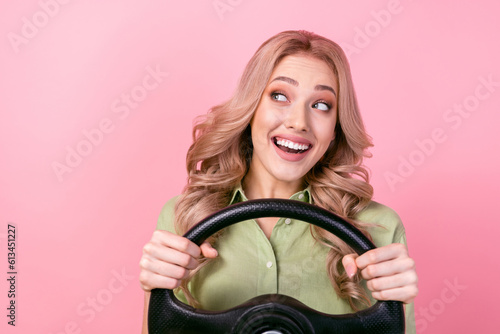 Portrait of charming cheerful girl hands hold wheel look empty space isolated on pink color background