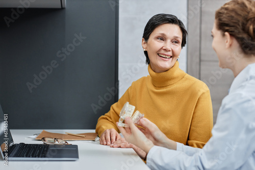 Portrait of smiling mature woman talking to dentist in dental clinic and consulting on tooth implantation, copy space