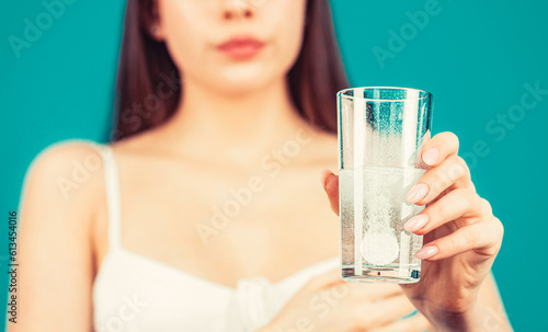 Woman taking a pill with a glass of water. Woman taking drugs to releave headache. Brunette take some pills, holds glass of water photo