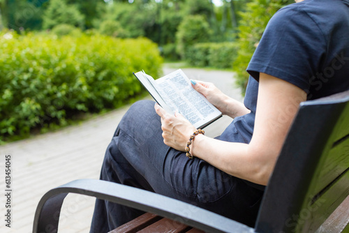 woman reading the bible sitting on a bench.