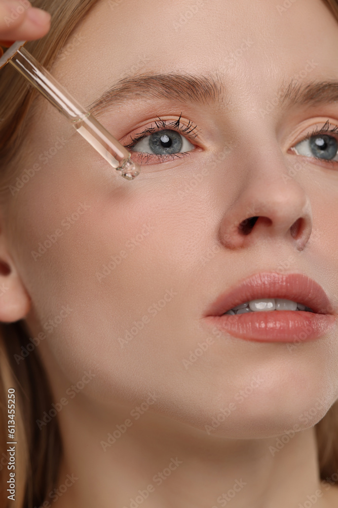 Woman applying essential oil onto face, closeup