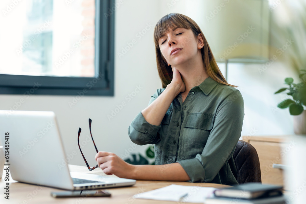 Stressed young business woman working with laptop in the office. Looking worried, tired and overwhelmed Stressed young business woman working with laptop in the office. Looking worried, tired and overwhelmed