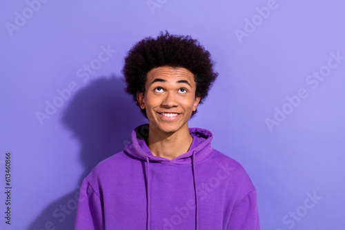 Photo of cheerful positive person beaming smile look interested up above empty space isolated on violet color background