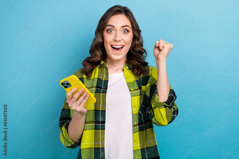 Photo of lucky sweet lady wear checkered jacket rising fist chatting instagram twitter telegram facebook isolated blue color background Photo of lucky sweet lady wear checkered jacket rising fist chatting instagram twitter telegram facebook isolated blue color background
