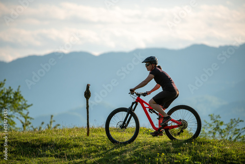 Female cycling on her mountain bike through the countryside on a sunny day. © gljivec