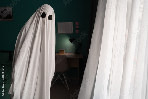 Ghost covered with a white ghost sheet on a bedroom. Halloween Concept
