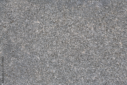Granite texture. Natural gray granite with a grainy pattern. Stone background. Solid rough surface of rock. Durable construction and decoration material. Close-up.
