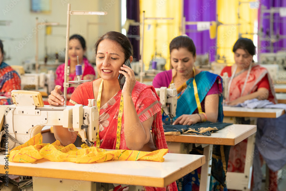Indian woman talking on smartphone while working at textile factory. Indian woman talking on smartphone while working at textile factory.
