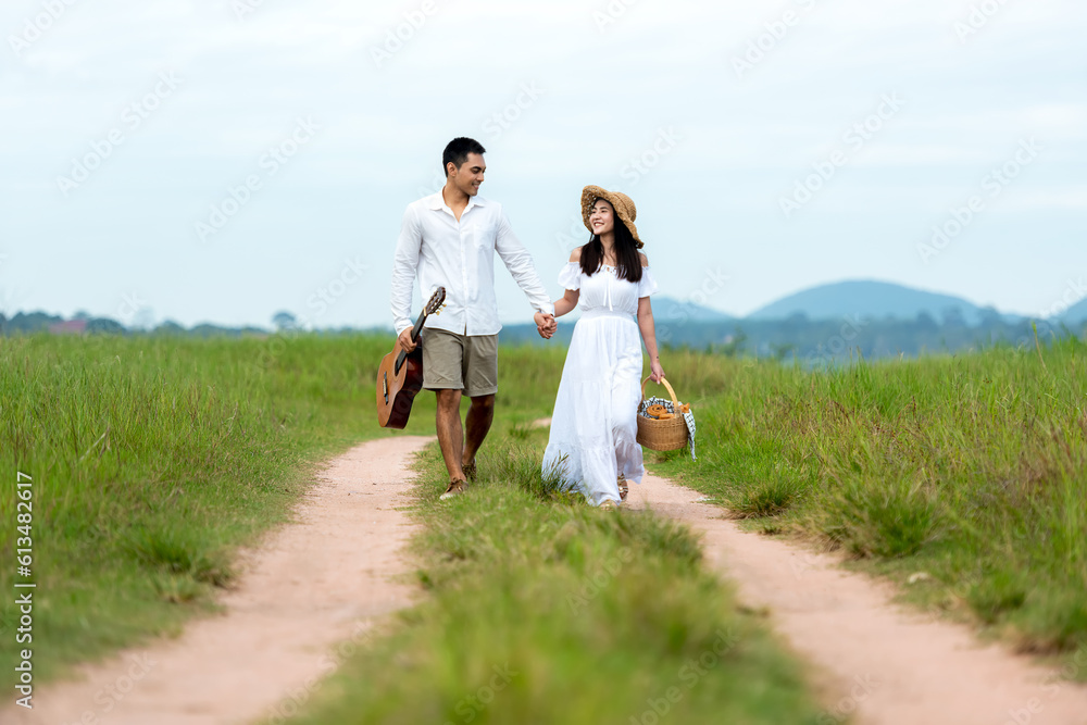 Lifestyle couple happy honeymoon in sunny time. Asian young couple sitting picnic and relax in the meadow in holiday. Romantic and In love. Lifestyle and Valentine concept Lifestyle couple happy honeymoon in sunny time. Asian young couple sitting picnic and relax in the meadow in holiday. Romantic and In love. Lifestyle and Valentine concept