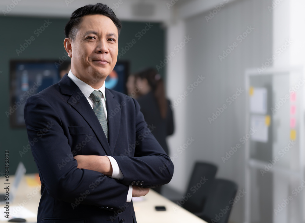 Portrait of Asian businessman standing in conference room arms crossed. Confident smart entrepreneur wears suit looking at camera smiling. Handsome businessperson meeting with colleagues in workplace. Portrait of Asian businessman standing in conference room arms crossed. Confident smart entrepreneur wears suit looking at camera smiling. Handsome businessperson meeting with colleagues in workplace.