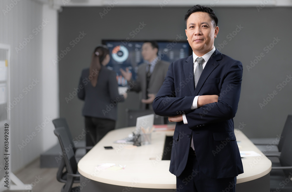 Portrait of Asian businessman standing in conference room arms crossed. Confident smart entrepreneur wears suit looking at camera smiling. Handsome businessperson meeting with colleagues in workplace. Portrait of Asian businessman standing in conference room arms crossed. Confident smart entrepreneur wears suit looking at camera smiling. Handsome businessperson meeting with colleagues in workplace.