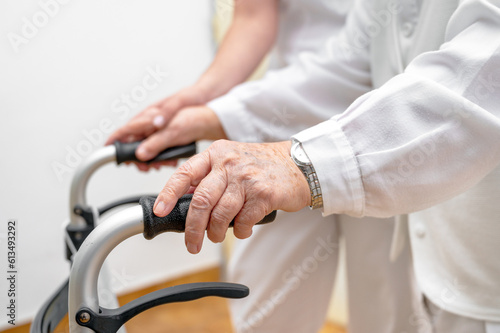 Nurse assists her senior patient on folding walker. Recuperation for elderly, seniors care, nursing home. High quality photo