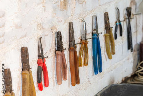 Various colours used pliers hanging on wall in the workshop