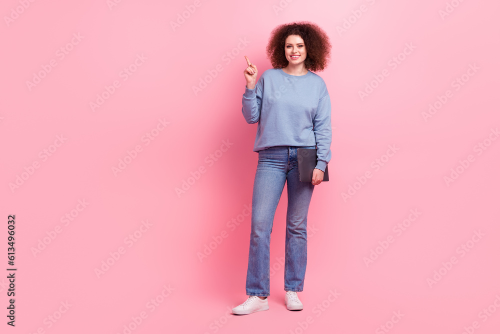 Full body cadre of young business lady wear blue sweatshirt jeans hold computer direct finger empty space isolated on pink color background Full body cadre of young business lady wear blue sweatshirt jeans hold computer direct finger empty space isolated on pink color background