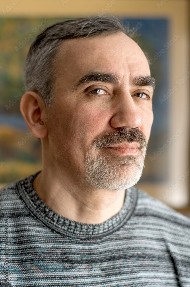 Adult middle aged man. He is wearing a casual sweater. Face with gray beard and thick eyebrows. Chest-length lifestyle portrait of matured caucasian person. Adult middle aged man. He is wearing a casual sweater. Face with gray beard and thick eyebrows. Chest-length lifestyle portrait of matured caucasian person.