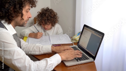 Father and son 9-year-old elementary school boy doing homework - doing school-given math exercises for the summer holidays - childhood lifestyle student with computer laptop 