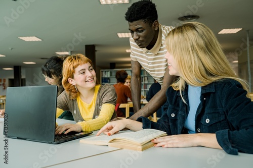 Фотография Diverse students sitting in library with laptop