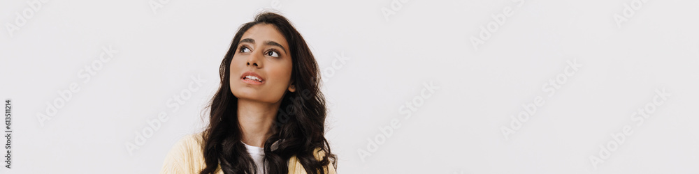 Young brunette indian woman looking upward while posing at camera Young brunette indian woman looking upward while posing at camera