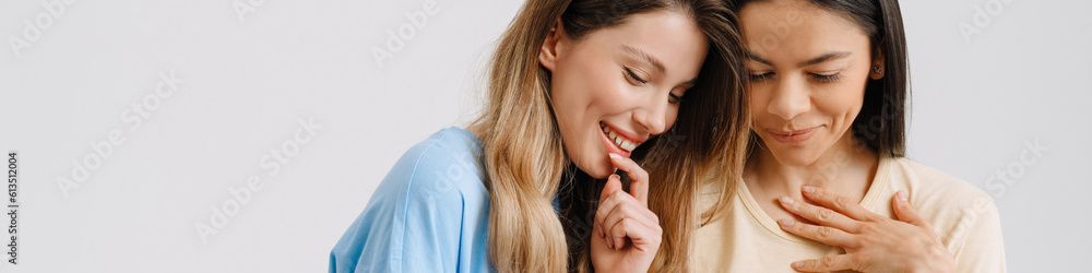 Two young brunette women posing at camera with cellphones Two young brunette women posing at camera with cellphones