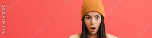 Young excited girl wearing hat posing at camera with cellphone