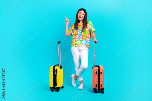 Full body photo of hipster black hair lady direct finger empty space resort hold suitbags isolated on aquamarine color background photo