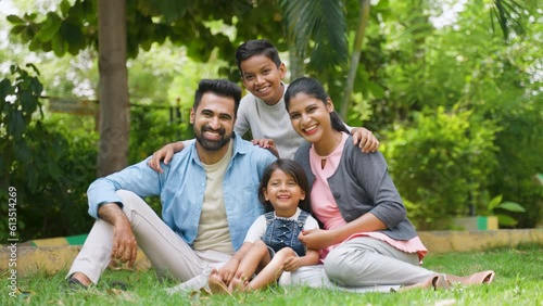 Happy indian family with sbling kids spending time together at park - concept of weekend holidays, family time and parenthood