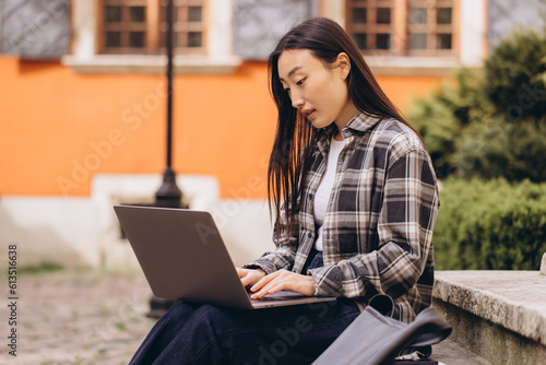Freelance young adult asian woman using laptop computer for work. Sitting at outdoor on day. Urban people lifestyle with modern technology. © anatoliycherkas