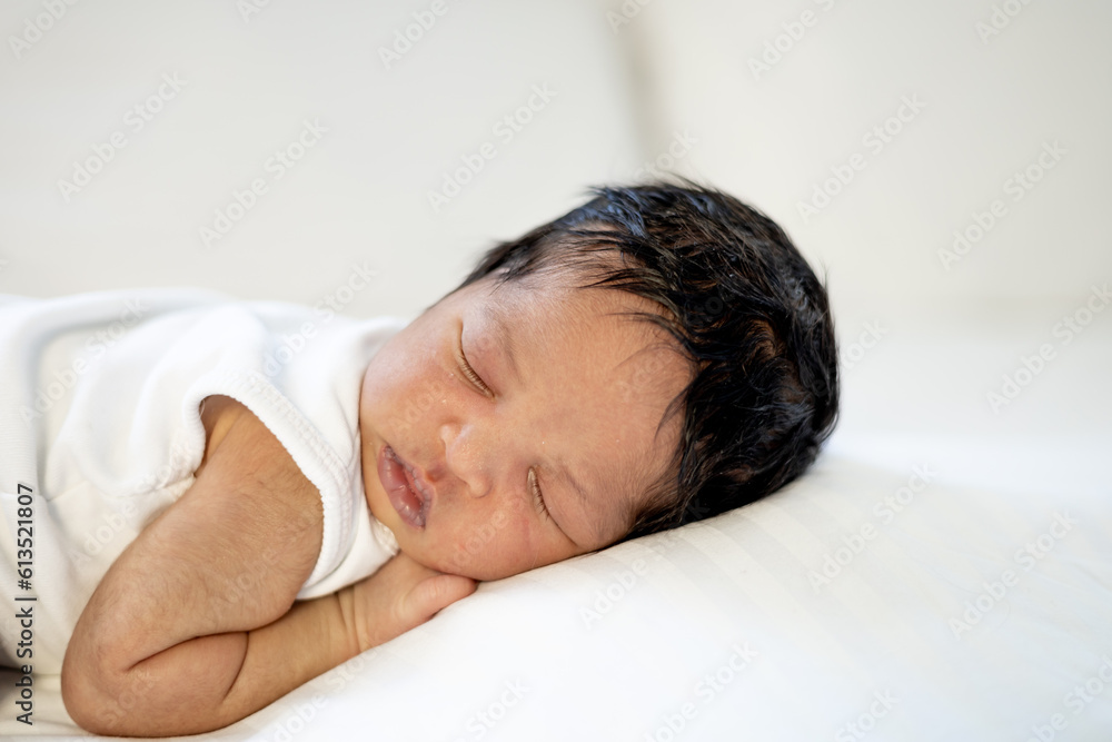a newborn black African-American baby is sleeping sweetly on his tummy, a small dark-skinned baby is lying on the bed in the bedroom in close-up a newborn black African-American baby is sleeping sweetly on his tummy, a small dark-skinned baby is lying on the bed in the bedroom in close-up