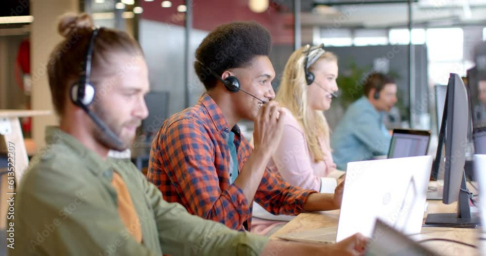 Happy biracial casual businessman and diverse colleagues using phone headsets, slow motion Happy biracial casual businessman and diverse colleagues using phone headsets, slow motion