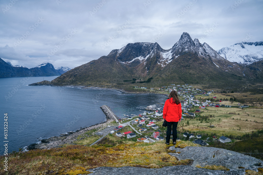 A woman stands atop a tranquil ridge in Norway. Landscape of senja island in northern norway, dark landscape of the norwegian fjords, hiking in norway