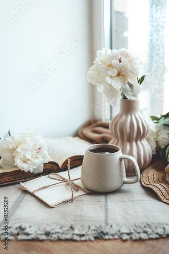 Cup of tea, straw hat, open book and peonies, spring still life