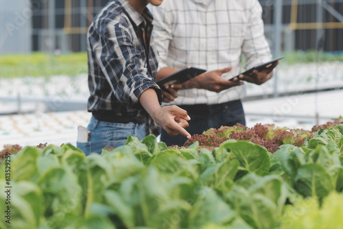 Female scientist examining a plants in greenhouse farm. scientists holding equipment for research plant in organic farm. Quality control for hydroponics vegetable farm.