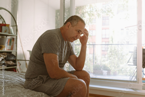 Canvas Print Middle-aged man in bedroom sitting on bed
