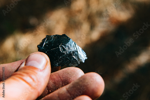A hand holds a chip of black obsidian in the Valles Caldera National Preserve, New Mexico photo