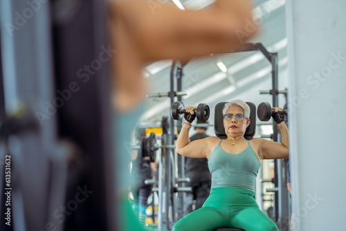 Senior woman doing exercises in the gym to stay healthy, trains muscles.