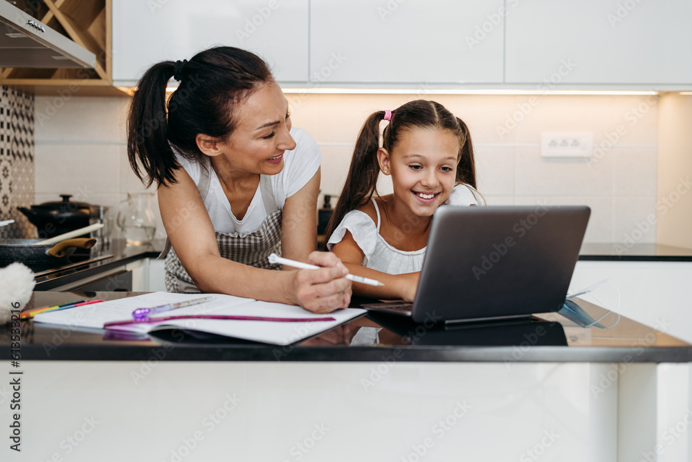 Young mother helping her daughter on e-learning session during virus pandemic crisis lockdown or quarantine. Illness prevention and new normal concept. Young mother helping her daughter on e-learning session during virus pandemic crisis lockdown or quarantine. Illness prevention and new normal concept.