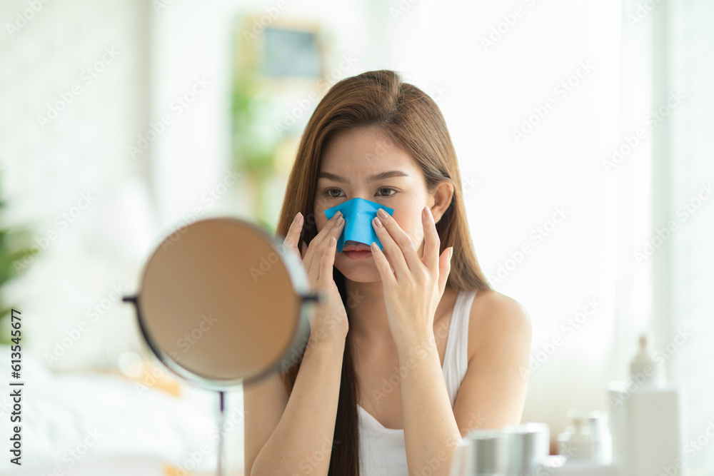 Asian young woman looking in mirror doing skin care touch cheek using oil film worry about oily face and beauty treatment at home,Wellness woman self care with beauty product at home - obrazy, fototapety, plakaty 