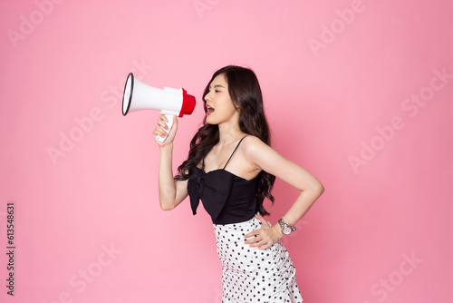 Asian woman smiling face holding megaphone shouting, posing isolated on pink pastel wall, photo studio background, with copy space