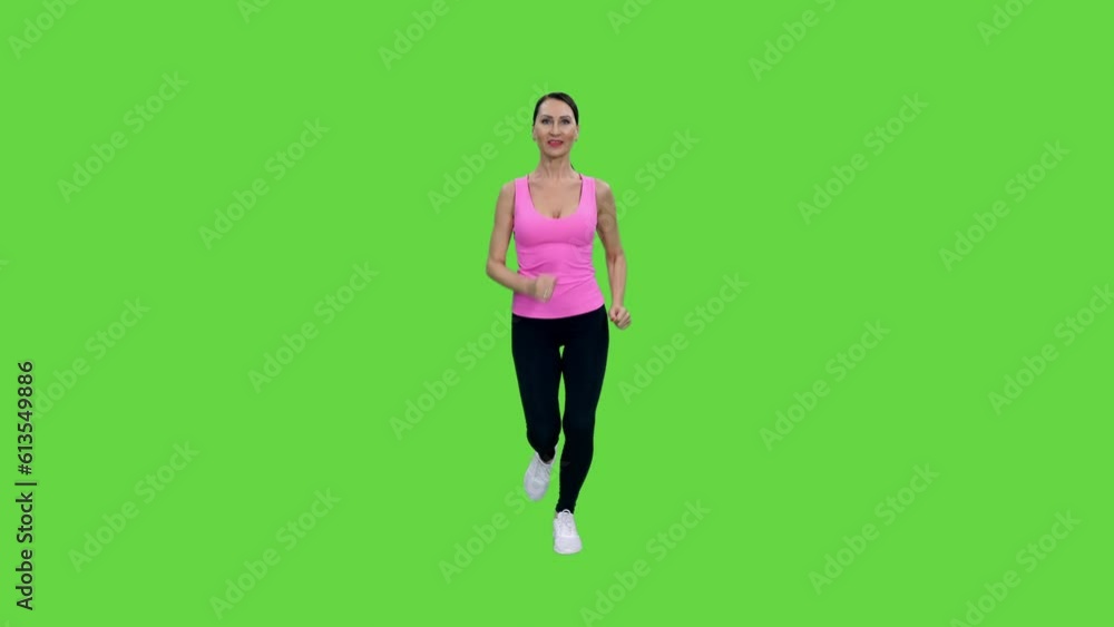 Smiling slim adult woman in pink tank top and black leggings jogging on green background, Front view, Chroma key, 4k pre-keyed footage Smiling slim adult woman in pink tank top and black leggings jogging on green background, Front view, Chroma key, 4k pre-keyed footage