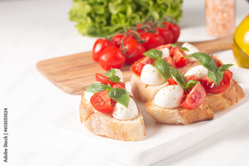 Tomato, basil and cheese fresh made caprese bruschetta. Italian tapas, antipasti with vegetables, herbs and oil on grilled ciabatta and baguette bread. Sandwich.