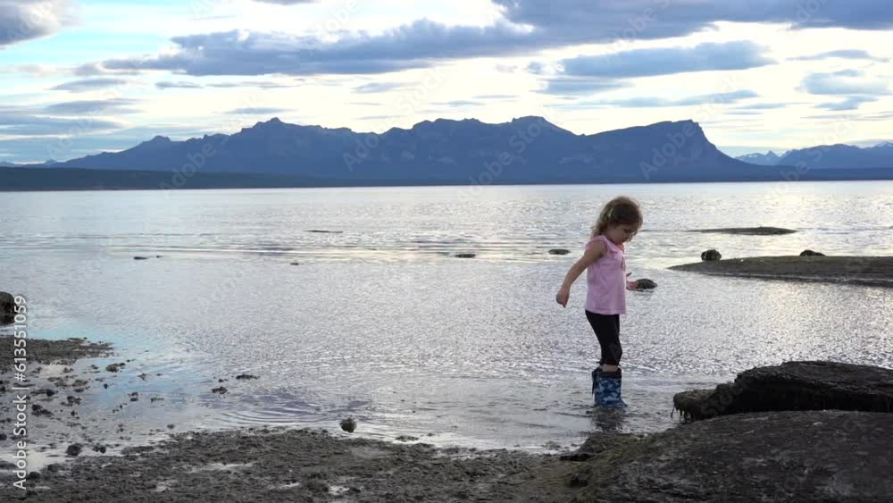 Little girl in rain boots playing and jumping in a water of a sea near the beach. . High quality FullHD footage Little girl in rain boots playing and jumping in a water of a sea near the beach. . High quality FullHD footage