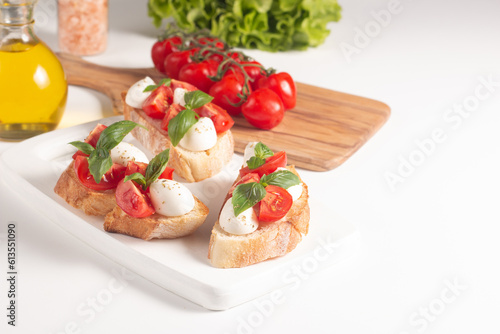 Tomato, basil and cheese fresh made caprese bruschetta. Italian tapas, antipasti with vegetables, herbs and oil on grilled ciabatta and baguette bread. Sandwich.