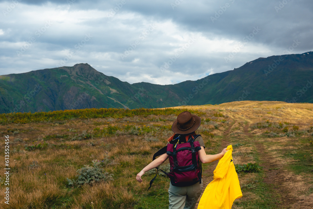 Woman in wide sun hat and backpack, tourist on hiking route to Koruldi Lakes, Svaneti region, Mestia Georgia. The concept of travel and active recreation. Summer day. Rear view