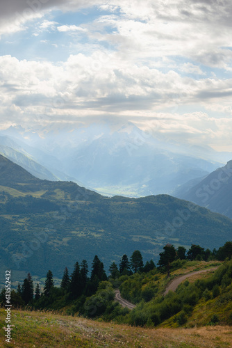 View of mountain tops, warm summer day, clouds in the sky, way to Ushba mountain and Koruldi lakes. Concept of vacation and travel to Georgia. Nature, Mestia, Svaneti mountains. Vertical photo