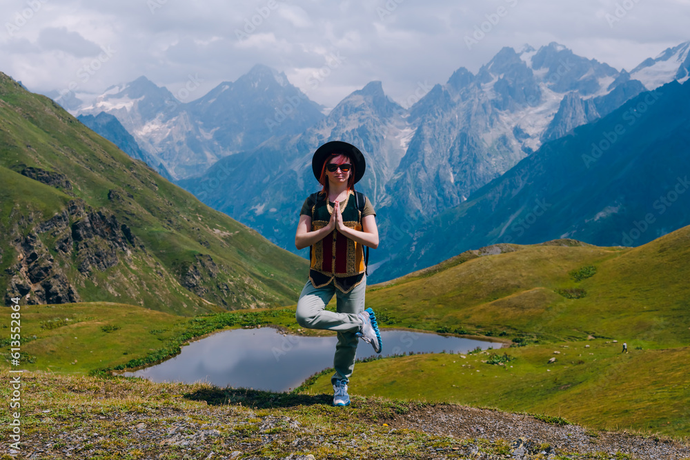 Young woman standing in the yoga position. Practices yoga. Koruldi lakes, Svaneti region, Georgia. Summer day in the mountains of the Caucasus. Spiritual mood and relaxation