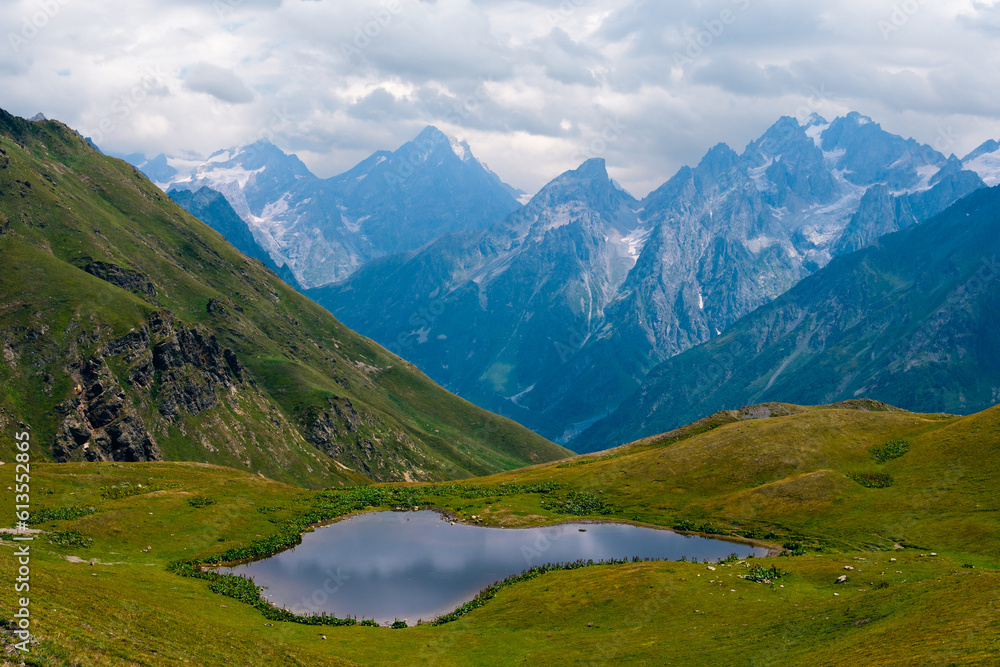 Koruldi lakes in Caucasus mountains, Mestia, Svaneti region, Georgia. Summer day, green hills, high mountain pasture for livestock, snow mountain peaks. Large panorama with high resolution